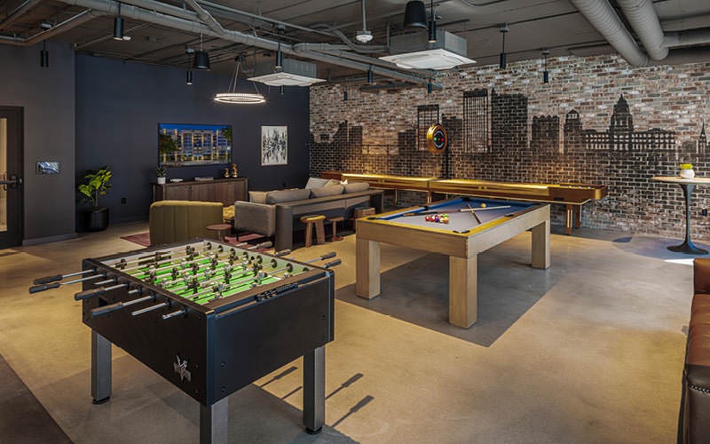 Broadstone Saratoga clubhouse with a mural of Downtown Boise skyline and a pool table, shuffleboard table, fuse ball table, and large TV screen