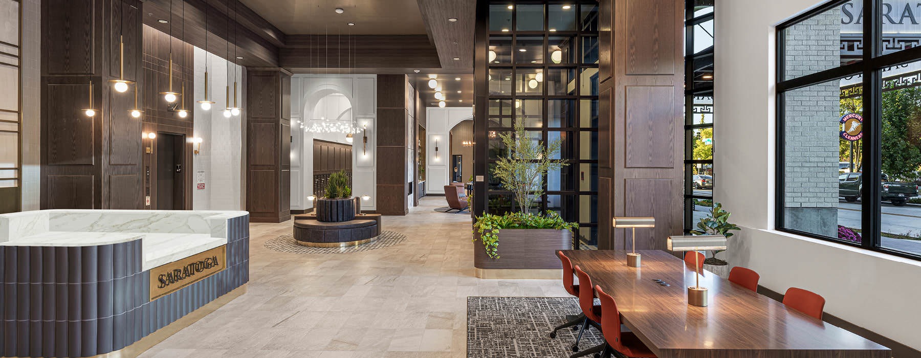 Bright coworking lounge at Broadstone Saratoga with large windows, modern work tables, comfortable seating, and stylish lighting.