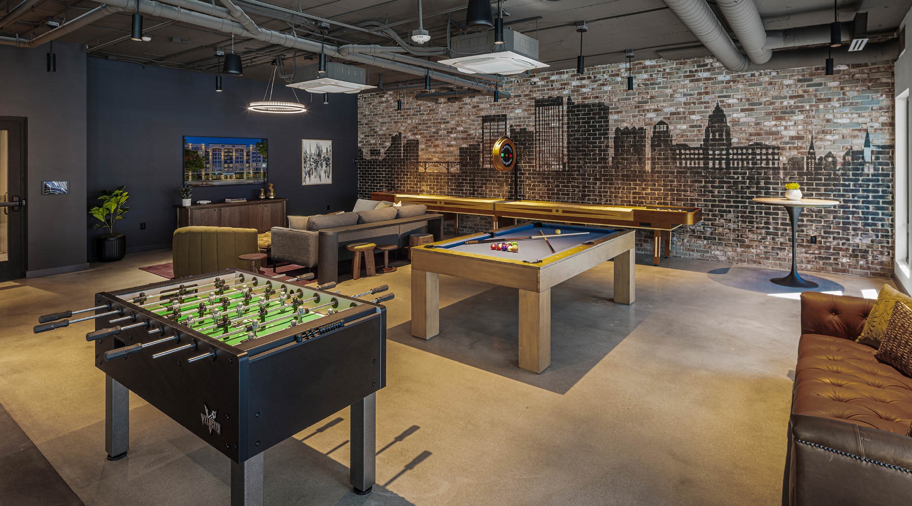 Broadstone Saratoga clubhouse with a mural of Downtown Boise skyline and a pool table, shuffleboard table, fuse ball table, and large TV screen