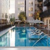 outdoor pool area with lounge chairs, in-pool loungers, and striped umbrellas surrounded by string lights and greenery