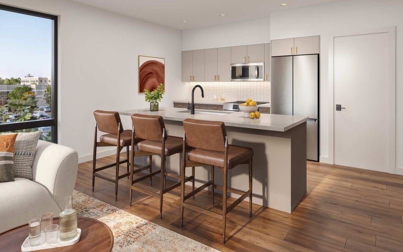 Modern kitchen with white cabinets, stainless steel appliances, and a large island with brown leather stools in a light-filled apartment.