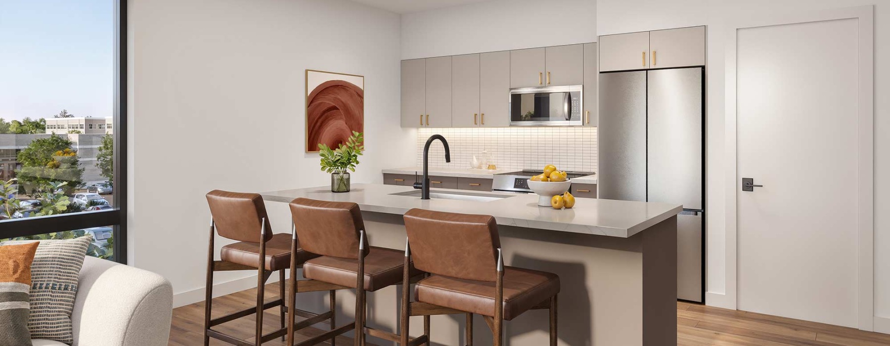 Modern kitchen with white cabinets, stainless steel appliances, and a large island with brown leather stools in a light-filled apartment.